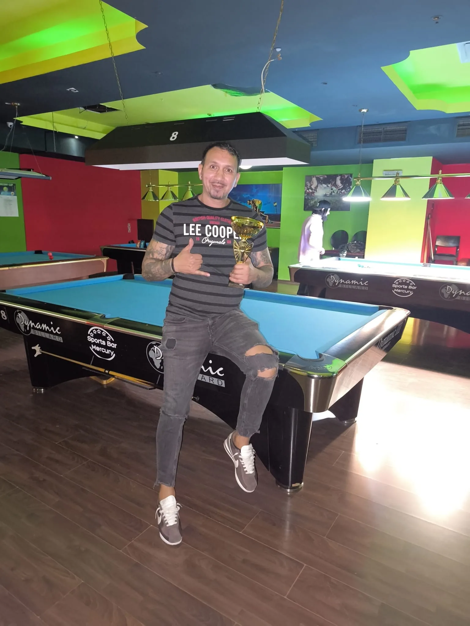 Câștigător cu trofeul, pe marginea unei mese de biliard Mercury