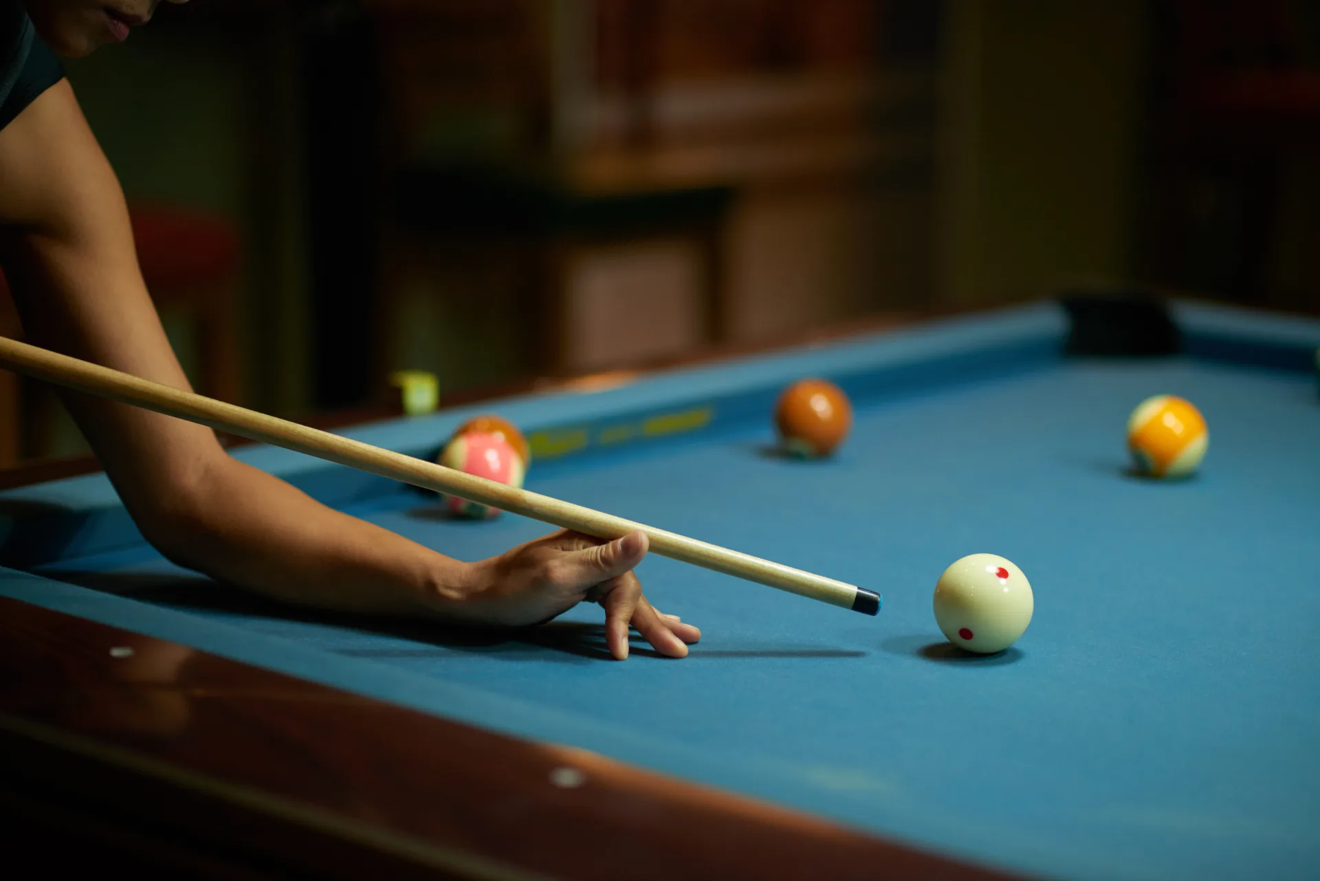 Player at the table in low light, cue set on the cue ball