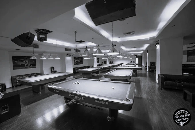 Mercury hall in black and white, perspective across multiple tables, pendant lights above